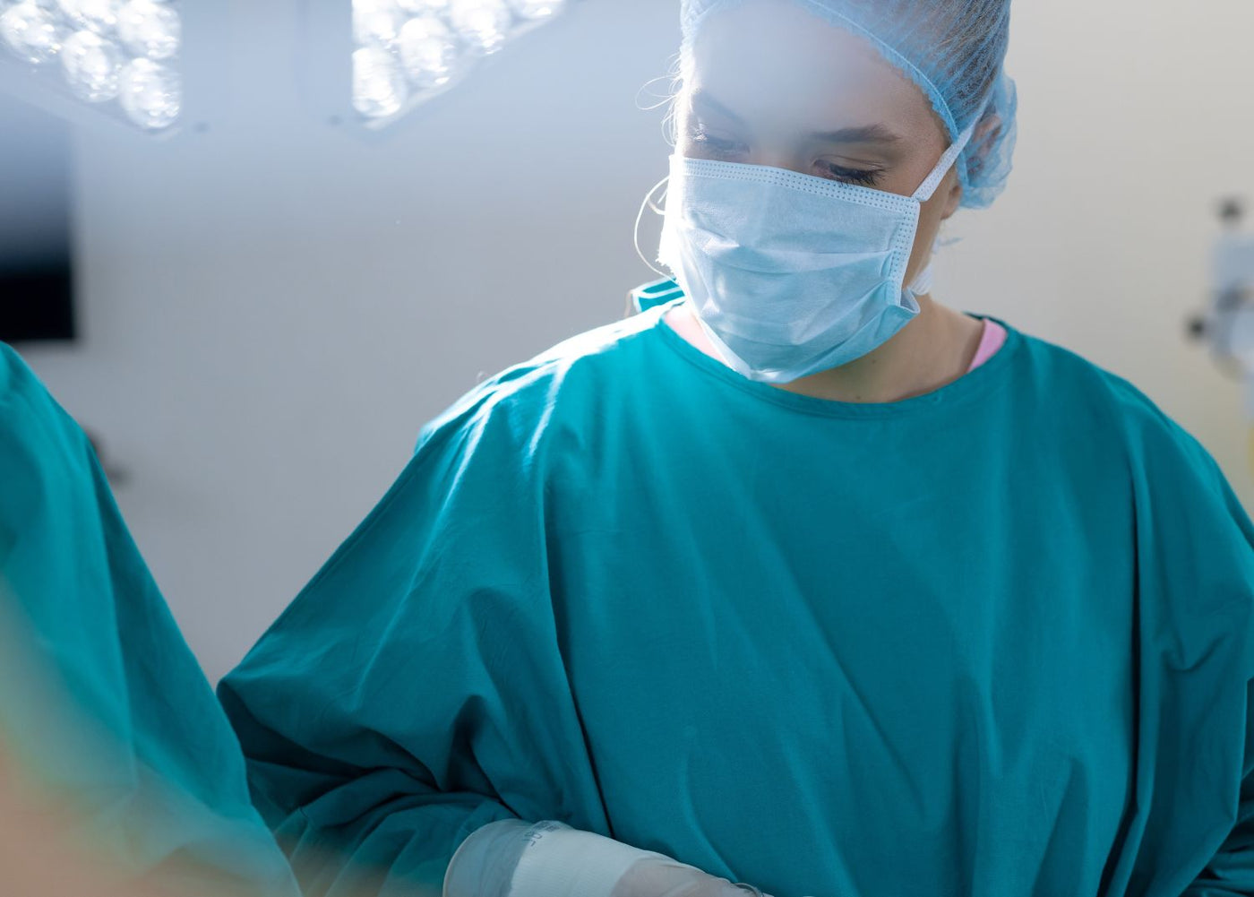Assistante portant un masque chirurgical et une tenue stérile bleue en bloc opératoire