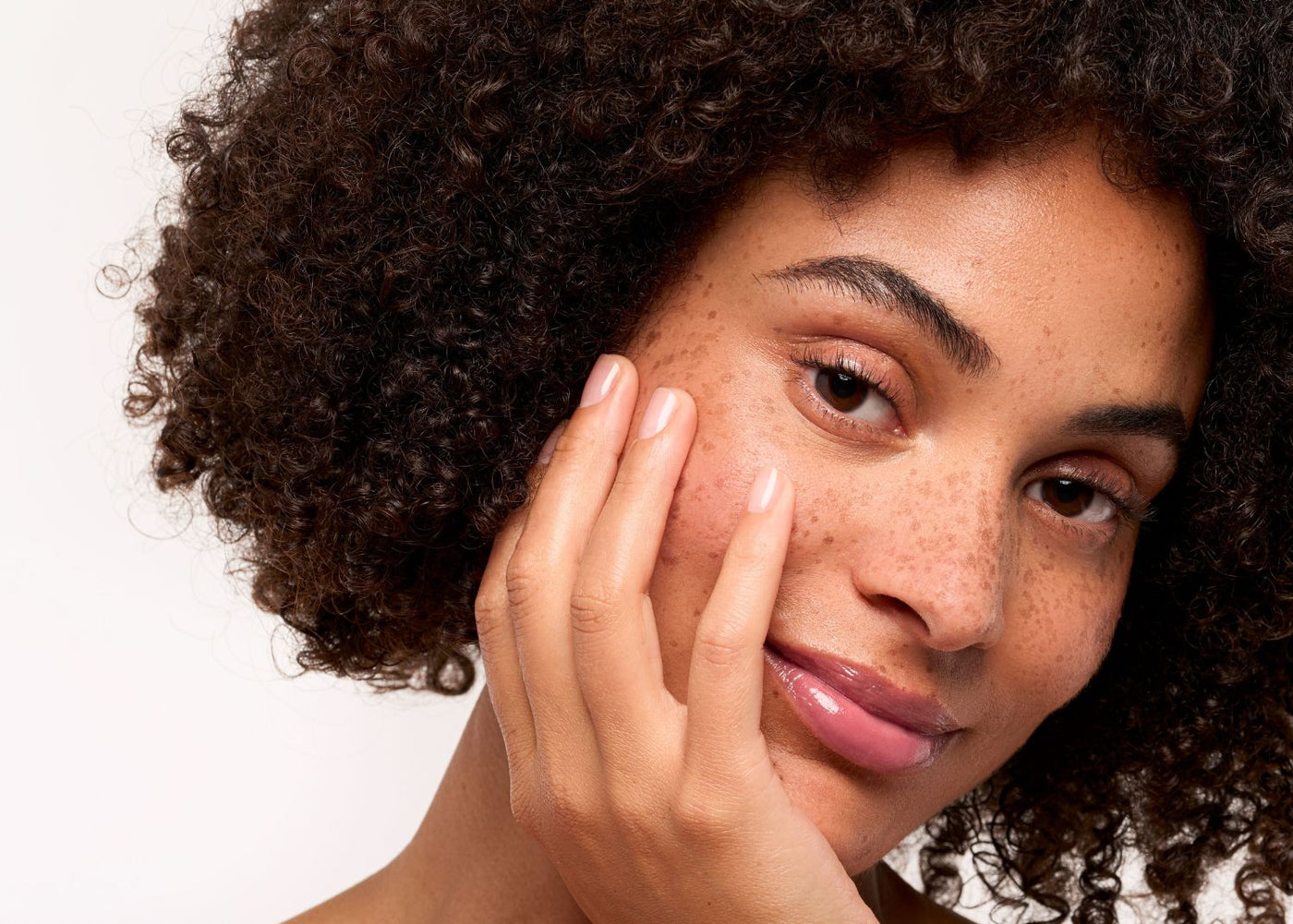 Gros plan sur le visage d’une femme métisse, ongles en amande blancs nacrés